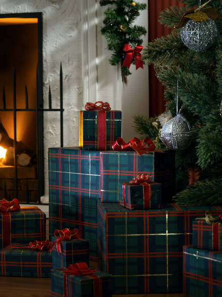view of wrapped gifts and fireplace with christmas tree on the back - Photo, Image