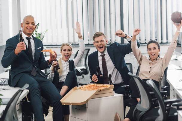cheerful young business people drinking beer and eating pizza in office  - 写真・画像