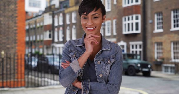 Knappe Afro-Amerikaanse vrouw in Londen kijkt camera gelukkig  - Foto, afbeelding