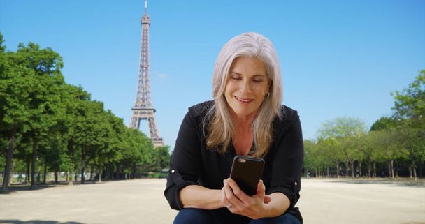 Yaşlı Bayan Paris Eiffel Tower yakınındaki smartphone denetler - Fotoğraf, Görsel