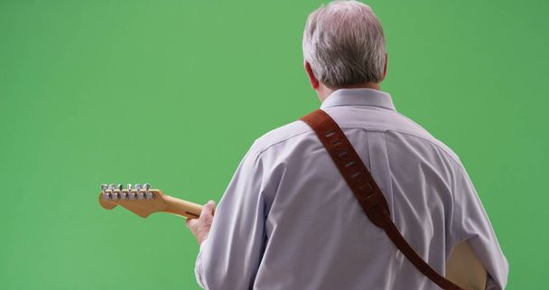 Rear view of mature white male playing electric guitar on greenscreen - Photo, Image