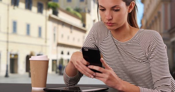 Donna caucasica con messaggi di caffè su smartphone al caffè italiano all'aperto
 - Foto, immagini