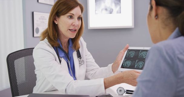 Young patient consulting with doctor over ct-scan indoors medical clinic - Photo, image