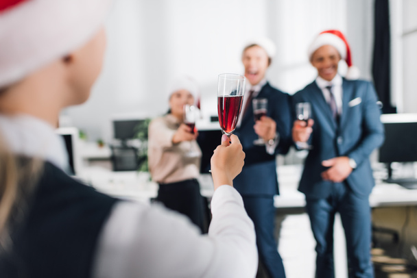 selective focus of young coworkers drinking wine and celebrating new year in office - Fotó, kép