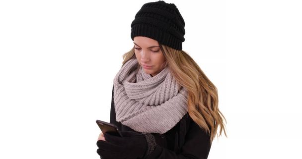 白い背景の上のモバイル デバイスと居心地の良い帽子やスカーフ テキスト メッセージで女性 - 写真・画像
