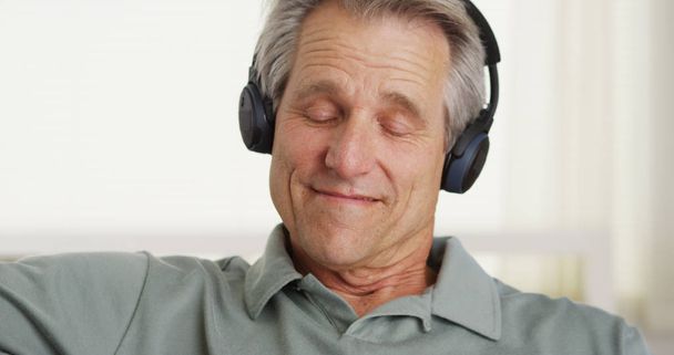 Closeup portrait of middle-aged white man enjoying music with headphones on - Foto, Imagen
