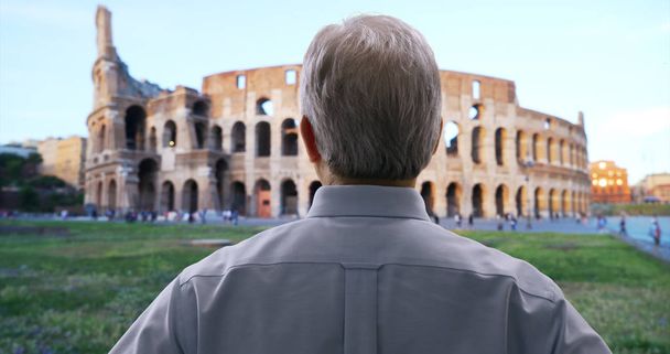 Vanhempi valkoinen herrasmies katselee ympärilleen, kun taas nähtävyydet lähellä Colosseum Roomassa
 - Valokuva, kuva