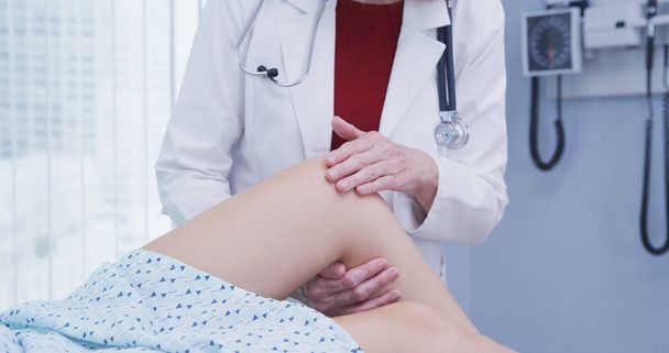 Mujer joven que se examina la rodilla después de sufrir una lesión en accidente
 - Foto, Imagen