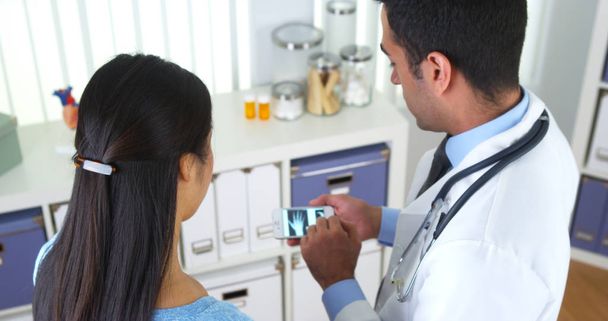 Mexicaanse arts smartphone met x-ray Toon aan patiënt - Foto, afbeelding