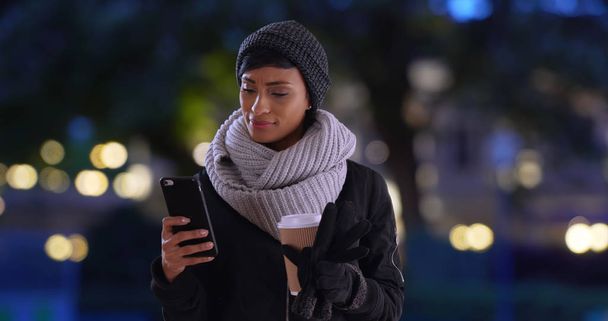 Hermosa joven negra con café lee mensaje de texto en su teléfono
 - Foto, Imagen