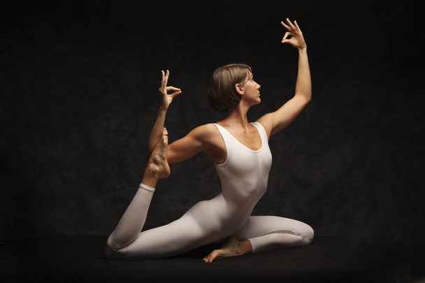 Siyah arka plan üzerinde yoga yaparken kadın - Fotoğraf, Görsel