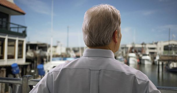 Portrait d'un homme blanc mature debout sur un port de mer regardant des voiliers
 - Photo, image