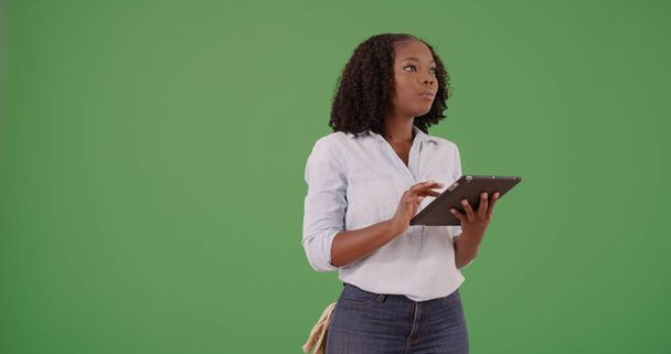 Νεαρή μαύρη γυναίκα στέκεται χρησιμοποιώντας μαξιλάρι πράσινη οθόνη υπολογιστή - Φωτογραφία, εικόνα