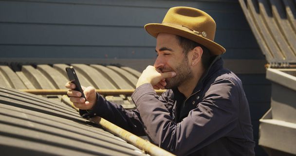 Joven Hipster utilizando el teléfono inteligente al aire libre
 - Foto, Imagen