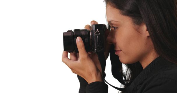 Side view of hipster girl in bomber jacket taking picture with camera in studio - Photo, Image