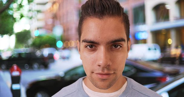 Wide angle close up shot of Hispanic man standing outside on street looking at camera - Photo, Image