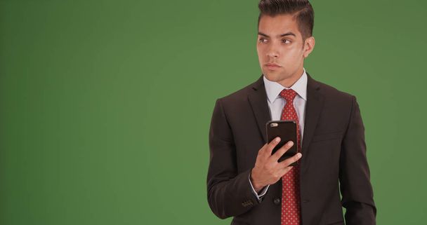 Millennial business man texting on mobile device on green screen - Fotó, kép