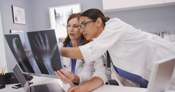 Two medical physicians viewing mri scans of patients hand indoors office - Photo, Image