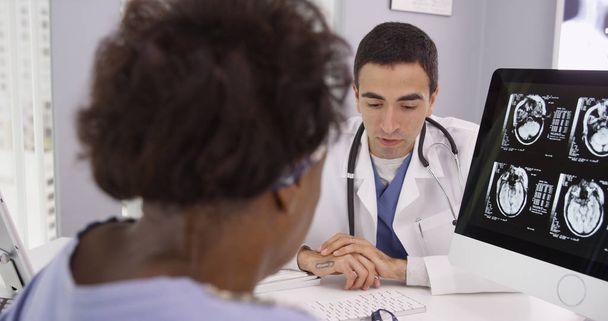 Nahaufnahme einer schwarzen Frau beim Betrachten von CT-Scans ihres Schädels auf dem Computer des Arztes - Foto, Bild