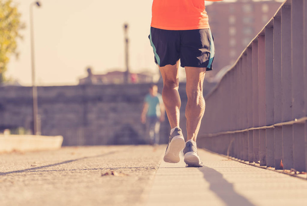 Close up image of strong athletic legs with ripped calf muscle of sport man running at sunset with copy space in urban city training Sport fitness Working out Marathon and healthy life style concept. - Photo, image