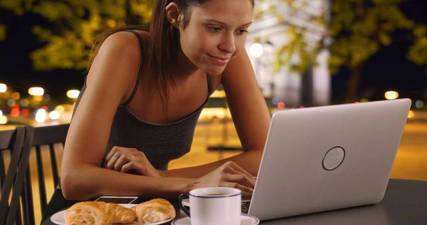 Kaukasische vrouw buiten at night met koffie browsen op laptop - Foto, afbeelding