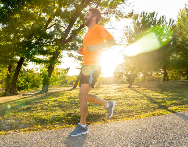 Happy runner in sportswear running training for Marathon outside in park at sunset on beautiful summer day in Sports Healthy lifestyle and Jogging Cross Country Training Workout Outdoors concept. - Foto, afbeelding