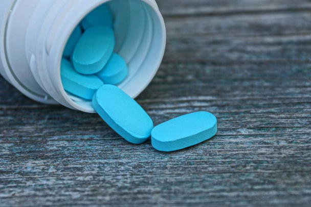 blue pills in white bottle on gray table - Photo, Image