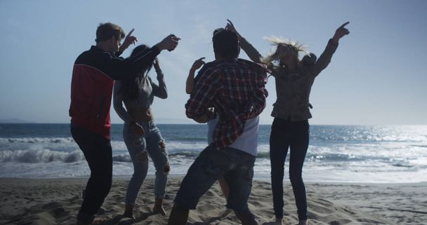 Веселая компания друзей танцует в песке на пляже
 - Фото, изображение