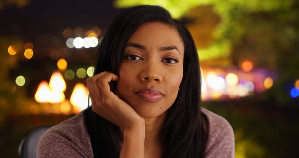 Pretty black woman outside at night looking at camera hand under her chin - Φωτογραφία, εικόνα