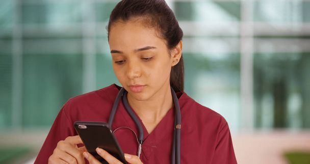 Um profissional médico usa seu telefone inteligente fora do hostpital
 - Foto, Imagem