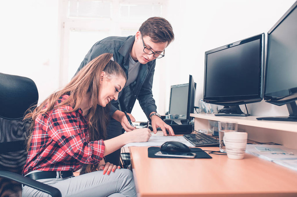 Trabajo en equipo exitoso: hombre y mujer jóvenes, consultando un informe juntos en un escritorio en la oficina
 - Foto, imagen