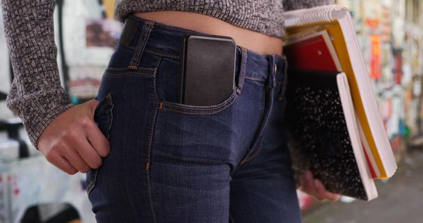 Tirador apretado de sección media de chica con teléfono móvil en el bolsillo por la pared de arte urbano
 - Foto, Imagen
