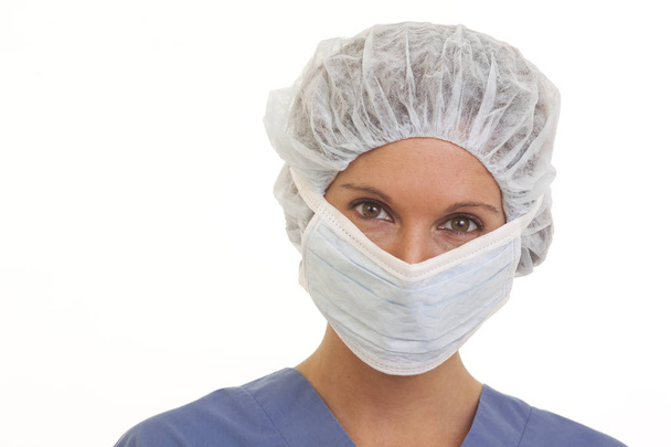 Close up portrait of serious young woman doctor in scrubs with mask and cap - Photo, image