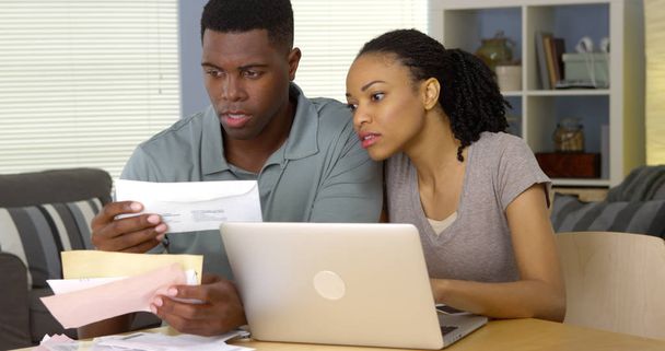 Serio joven negro pareja pagar facturas en línea con ordenador portátil
 - Foto, Imagen
