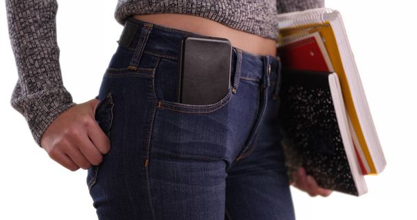 Primer plano de la chica universitaria llevando libros con teléfono en el bolsillo sobre fondo blanco
 - Foto, imagen