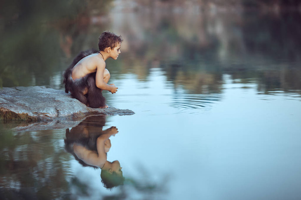 Caveman. Little boy sitting on the beach and looks at the water - Fotó, kép
