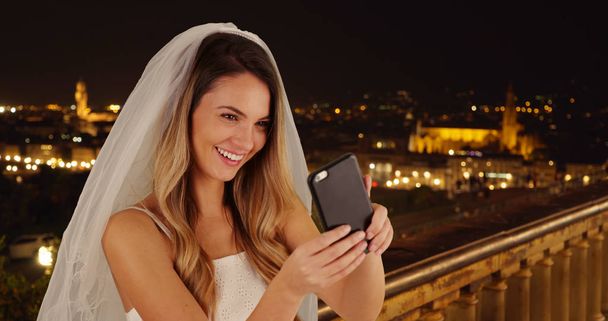 Joyful bride taking fun selfies in Florence on beautiful night - Photo, image