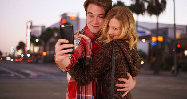 Millennial couple or friends posing for selfie together downtown in evening - Foto, imagen