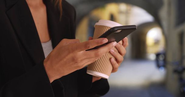 Close up shot of female hands texting on smartphone and drinking coffee - Photo, Image