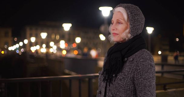 Senior mujer caucásica de pie por puente en la fría noche de invierno en la ciudad
 - Foto, imagen