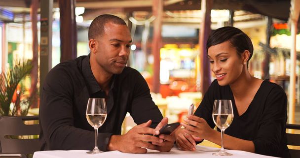 Μια αφρικανική αμερικανική ζευγάρι χρησιμοποιούν τα κινητά τους τηλέφωνα, ενώ τρώει δείπνο - Φωτογραφία, εικόνα