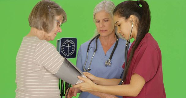 RN studenta, aby si vyšší krevní tlak pacienta na zelené obrazovce - Fotografie, Obrázek