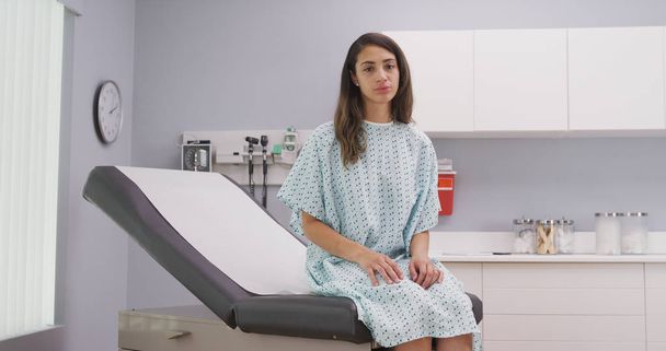 Primo piano di bella donna latina seduta sulla sedia medica in clinica ospedaliera
 - Foto, immagini
