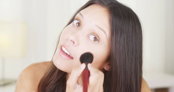 Mixed race woman applying makeup on face - 写真・画像