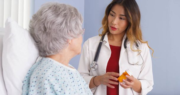 Asiatique médecin parler à une femme âgée au lit au sujet de médicaments sur ordonnance
 - Photo, image