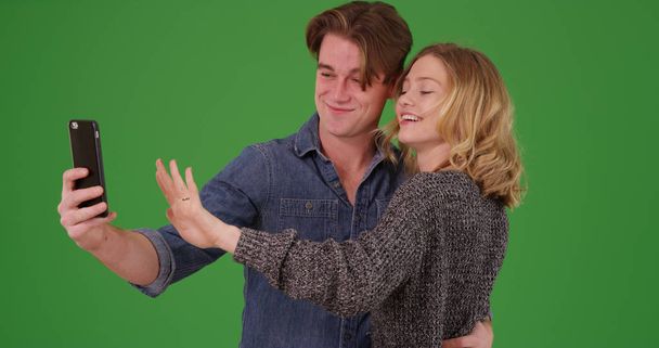 Happy engaged couple taking picture with smartphone on green screen - Foto, Bild