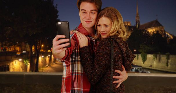 Happy young couple taking fun selfies in Paris at night - Photo, Image