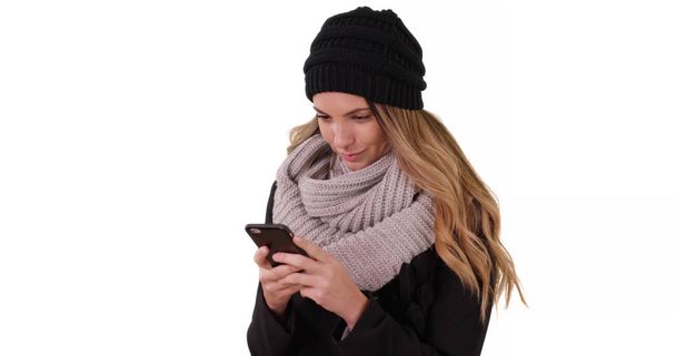 白い背景の上のモバイル デバイスと居心地の良い帽子やスカーフ テキスト メッセージで女性 - 写真・画像