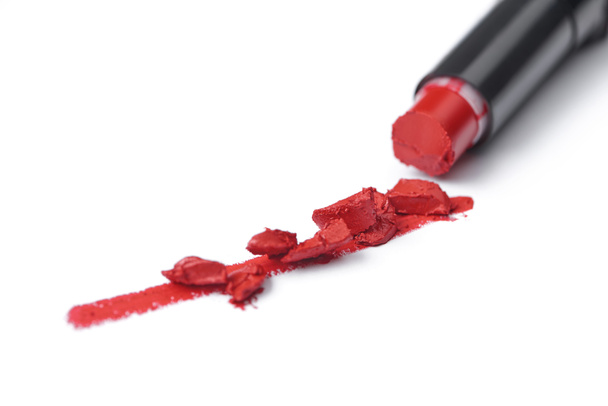 Close-up van gebroken rode lippenstift op witte achtergrond - Foto, afbeelding