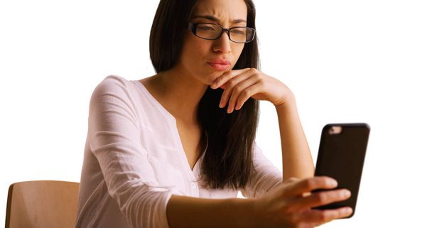 Una mujer hispana usa su teléfono inteligente sobre un fondo blanco
 - Foto, imagen